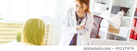 A beautiful young girl in a white robe is standing near a computer desk in the office and A beautiful young girl in a white robe is standing near a computer desk in the office and 45217474