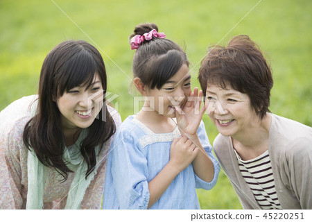 Three generation family talking secretly in the meadow Three generation family talking secretly in the meadow 45220251