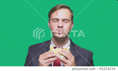 businessman eating a sandwich on a green background. quick lunch concept 45224214