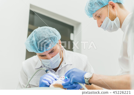 Doctor used microscope. Dentist is treating patient in modern dental office. Operation is carried 45226221