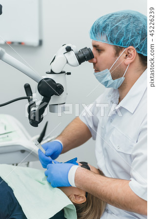 Doctor used microscope. Dentist is treating patient in modern dental office. Operation is carried 45226239