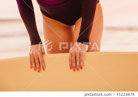 Surf girl with surfboard on beach at sunset 45228676