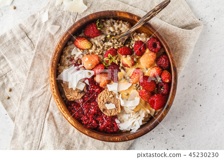 Trendy vegan bowl of oatmeal porridge with berries 45230230