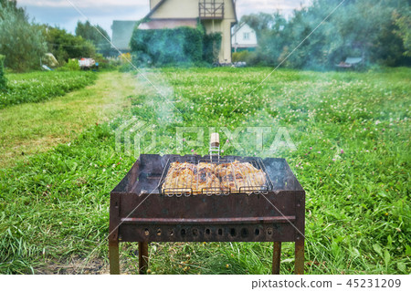 Preparing a chiken in a suburban area using a chairgrill and grill grid outdoors 45231209