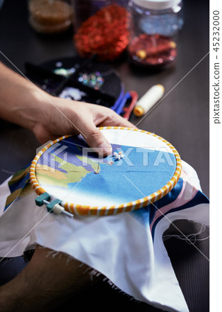 Man embroidering with beads Man embroidering with beads 45232000