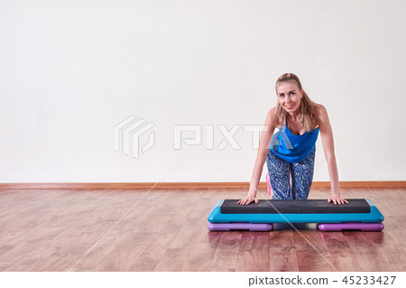 Young sportive woman exercising in gym using step platform, copy space. Young sportive woman exercising in gym using step platform, copy space. 45233427