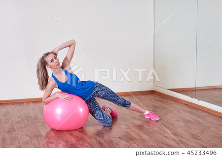 Athletic woman makes exercises on a fitness ball , indoors gym. Athletic woman makes exercises on a fitness ball , indoors gym. 45233496