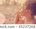 Five year old beautiful little girl blows soap  45237268