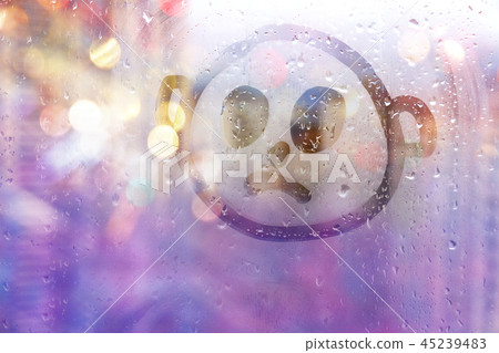 Foggy glass on window with drawn sad face concept photo with copy space on background of lilac bokeh Foggy glass on window with drawn sad face concept photo with copy space on background of lilac bokeh 45239483
