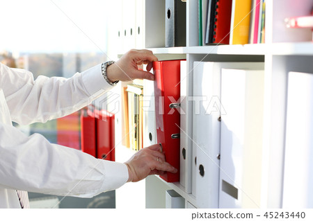 Male arms pick red file folder from office book shelf 45243440