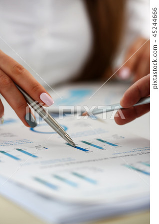 Female arm holding silver pen point in financial graph 45244666
