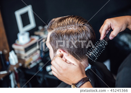 the master in the barbershop shaves and cuts man 45245366