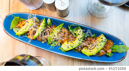 Delicious salmon tartare garnish with avocado on blue plate Delicious salmon tartare garnish with avocado on blue plate 45251089