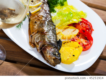 Picture of tasty baked whole trout with potatoes, greens and tomatoes 45251914