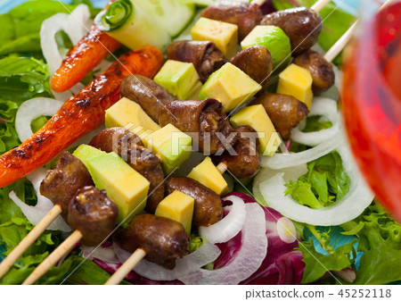 Tasty shish kebab from chicken hearts with avocado and lettuce at plate 45252118