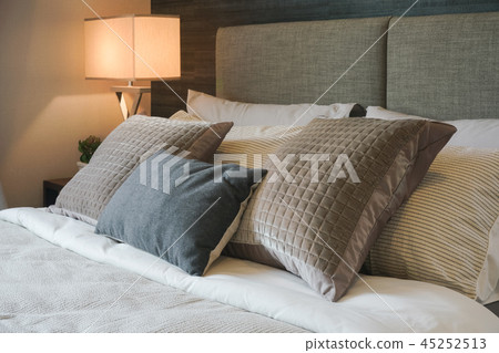 Gray and brown pillow on bed with reading lamp Gray and brown pillow on bed with reading lamp 45252513