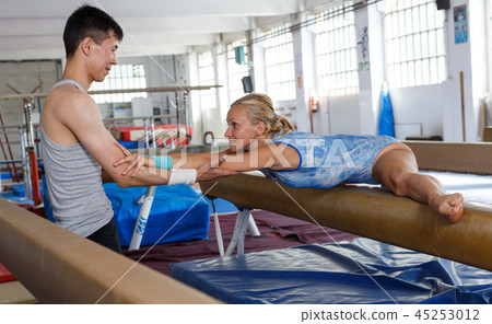 Woman doing exercises on balance beam Woman doing exercises on balance beam 45253012