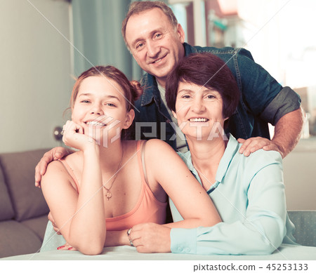 Smiling woman with her parents are posing at the table Smiling woman with her parents are posing at the table 45253133