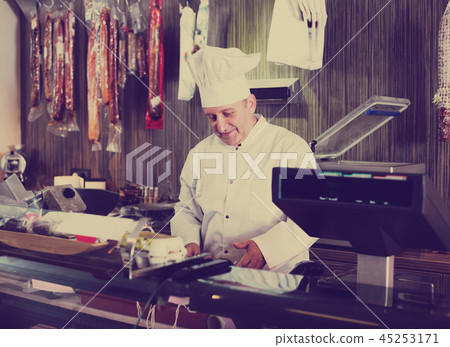 Male seller posing with wursts in butchery 45253171