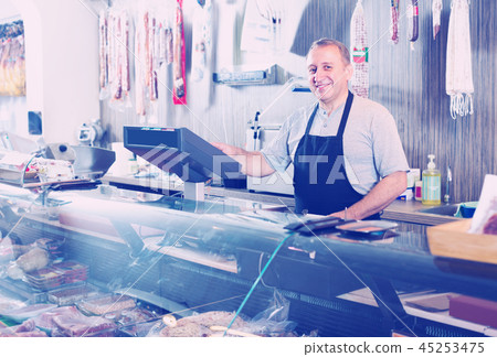 butcher with smoked meat at counter 45253475