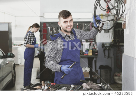 Man master is choosing instruments for work in workshop. Man master is choosing instruments for work in workshop. 45253595