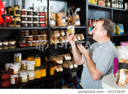 man looking at assortment of grocery products in shelves man looking at assortment of grocery products in shelves 45253634