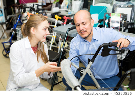 Female consultant offering wheelchair to mature customer Female consultant offering wheelchair to mature customer 45253836