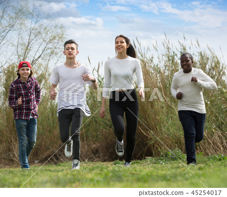 Portrait of four teenagers running on field Portrait of four teenagers running on field 45254017