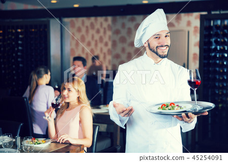 chef with dishes on serving tray welcoming 45254091