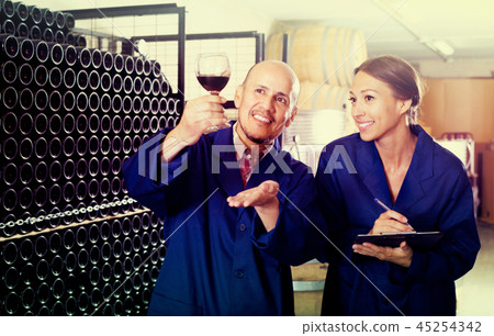 man and woman winemakers in wine cellar . man and woman winemakers in wine cellar . 45254342