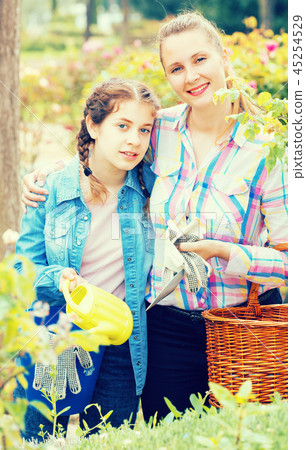 happy young woman and teen with gardening tools in outdoors happy young woman and teen with gardening tools in outdoors 45254529