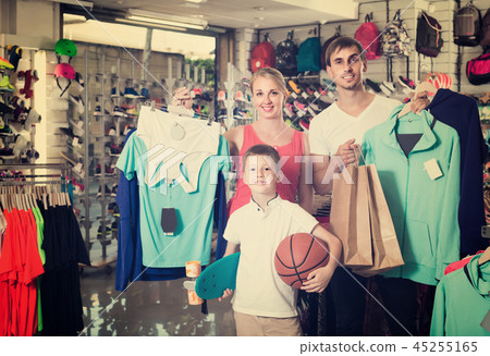 man and woman with boy choosing t-shirts and other goods in sport shop man and woman with boy choosing t-shirts and other goods in sport shop 45255165