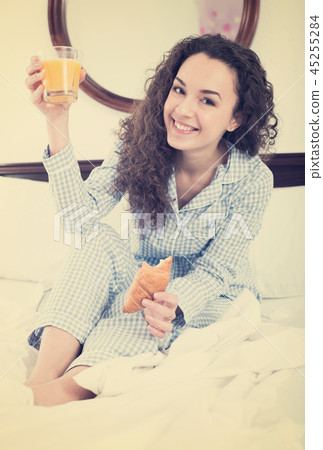 Female brunette with pastry and juice in bed Female brunette with pastry and juice in bed 45255284