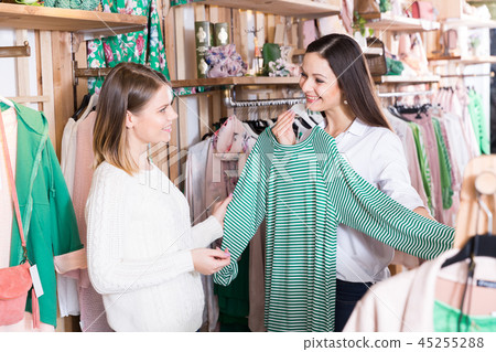 Smiling women choosing green sweater in the modern shop Smiling women choosing green sweater in the modern shop 45255288