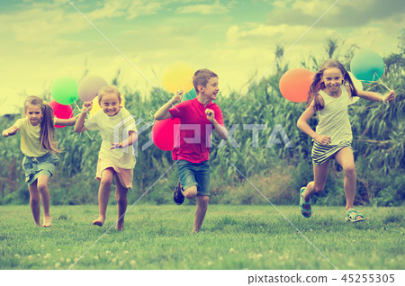 Four cheerful kids running on green lawn Four cheerful kids running on green lawn 45255305