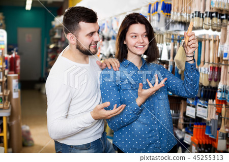 Couple examining various painting brushes Couple examining various painting brushes 45255313