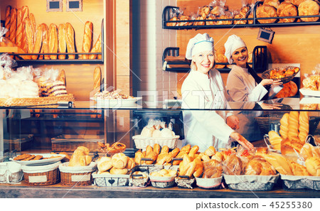 Bakery staff offering bread 45255380