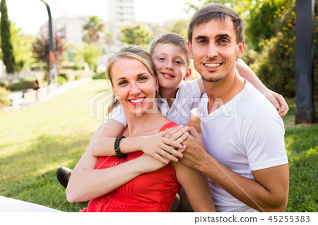 smiling family of three on green meadow . smiling family of three on green meadow . 45255383