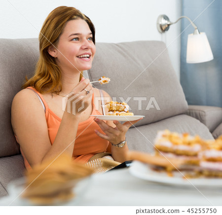 Cheerful female eating sweet cake at home 45255750