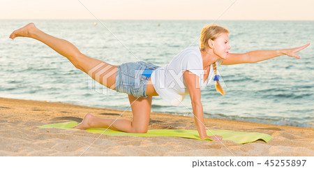 Smiling adult woman in white T-shirt is doing excercises on endurance Smiling adult woman in white T-shirt is doing excercises on endurance 45255897