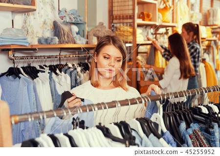 Young woman customer looking blue shirt in the showroom 45255952