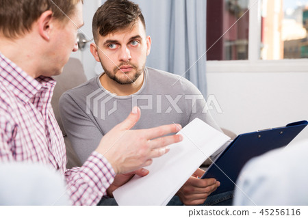 Troubled man discussing documents with partner on couch 45256116