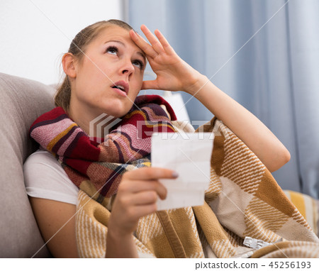 Sad young female reading recipe with pills 45256193