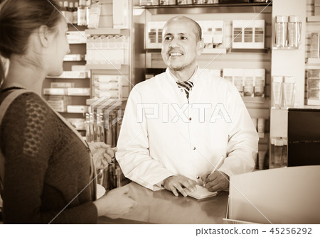 Pharmacist serving client in pharmacy . 45256292