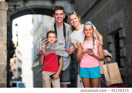 Man and woman with children are using paper map and phone 45256325