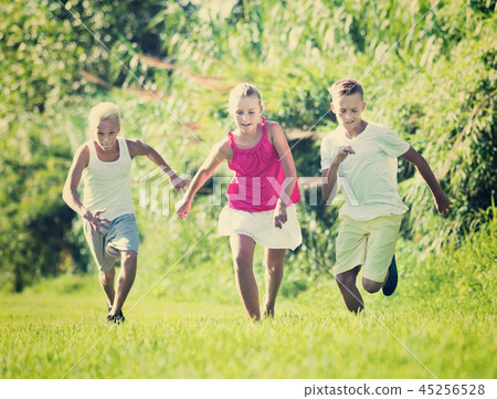 Group of laughing children having fun together outdoors running Group of laughing children having fun together outdoors running 45256528