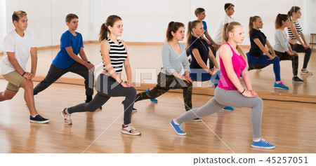 Teenage boys and girls with trainer stretching in dance hall 45257051