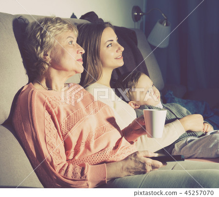 Two women and toddler are enjoying of watch film in evening Two women and toddler are enjoying of watch film in evening 45257070