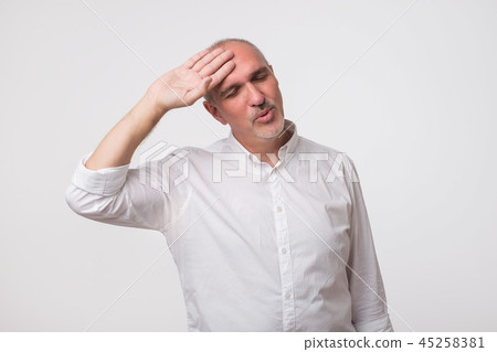 Mature man in white shirt looking exhausted. He with tired face wipes forehead. Mature man in white shirt looking exhausted. He with tired face wipes forehead. 45258381