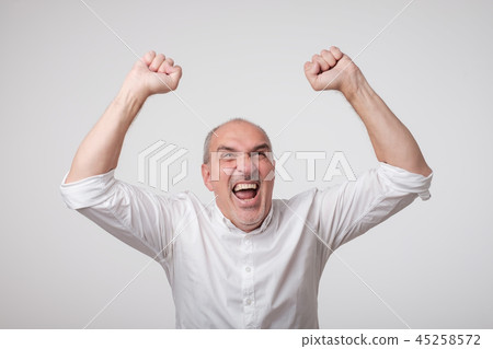 Portrait of mature european man with fists up. He is celebrating winning. Portrait of mature european man with fists up. He is celebrating winning. 45258572